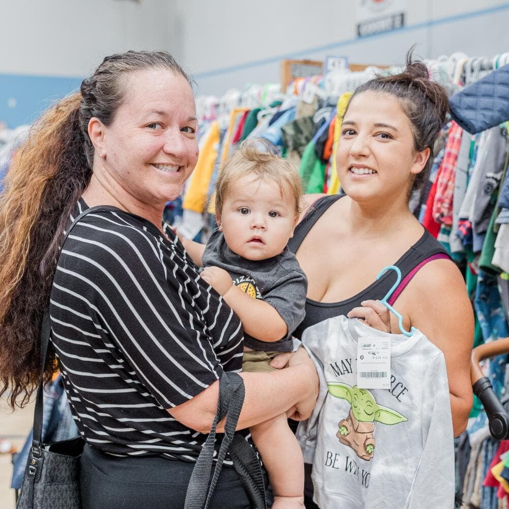 A mom, abuela and granddaughter attend a JBF sale in Texas. Abuela is holding a baby.