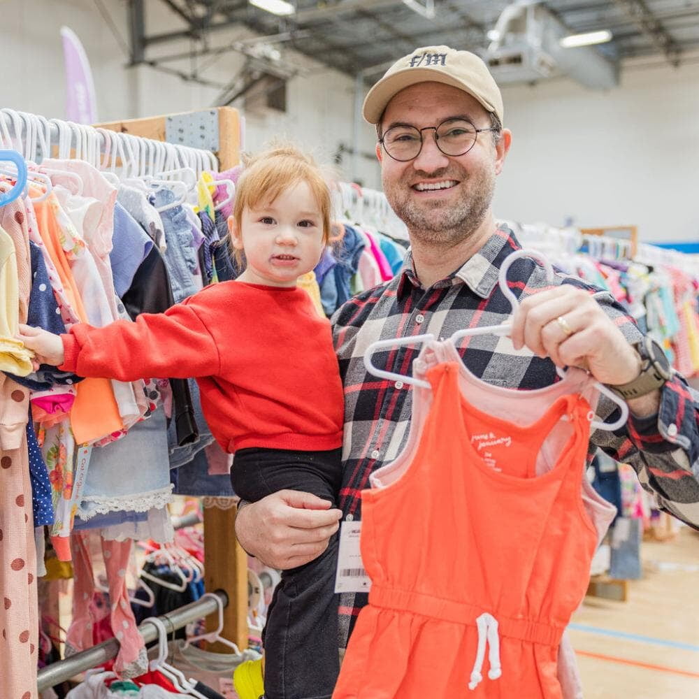 Dad shopping with small child in his arms.