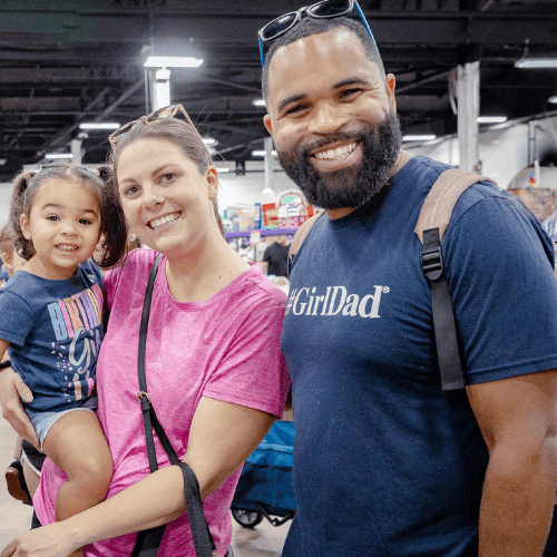 Dad and Mom holding a child shopping at JBF