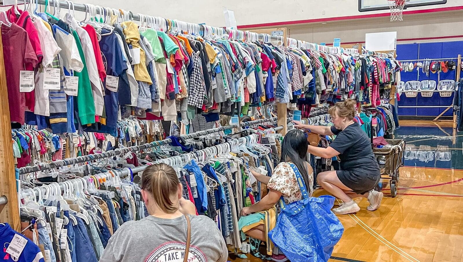 Mom and grandmother stand together, a few pieces of clothing in grandmom's hands, as they shop together for their family.